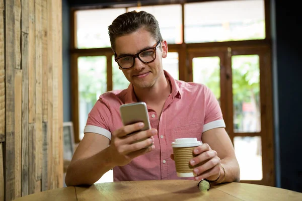 Człowiek przy użyciu telefonu komórkowego przy stoliku w kawiarni — Zdjęcie stockowe
