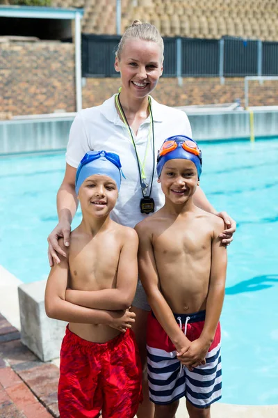 Instrutor de natação com meninos na beira da piscina — Fotografia de Stock