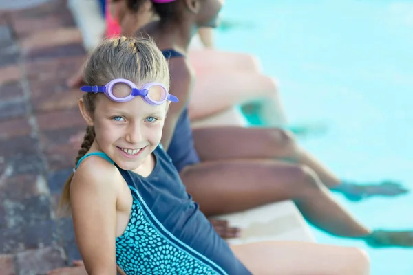 Glad flicka sitter med vänner vid poolen — Stockfoto