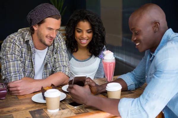 Homem mostrando telefone celular para amigos à mesa — Fotografia de Stock