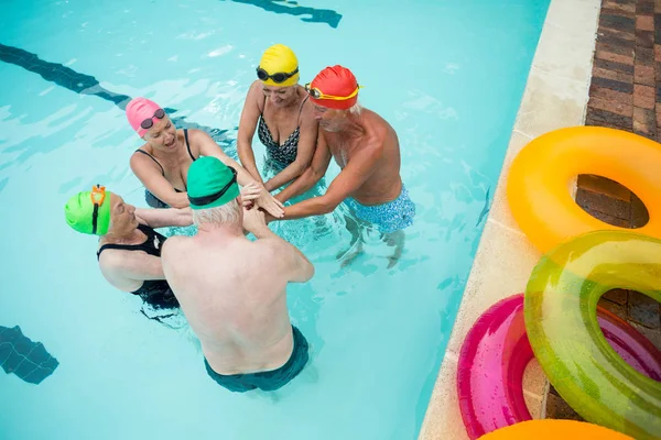 Seniores nadadores empilhando as mãos na piscina — Fotografia de Stock