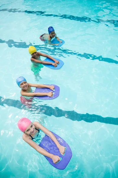 Дети, плавающие в бассейне с помощью кикборда — стоковое фото