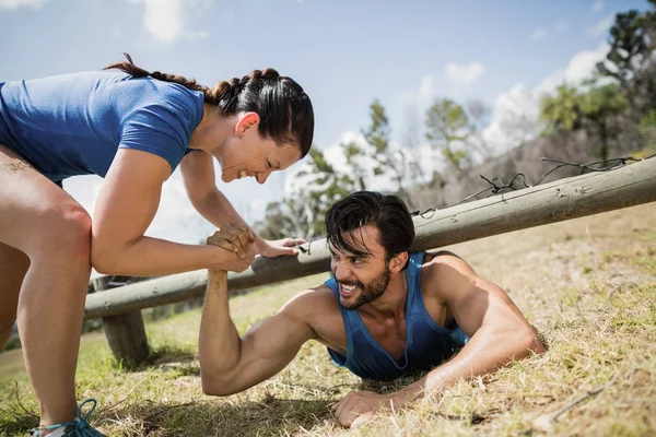 Vrouw helpen mens kruipen onder het net passen — Stockfoto