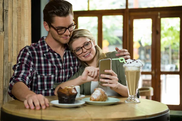 Älskande par använder smart telefon vid bord — Stockfoto
