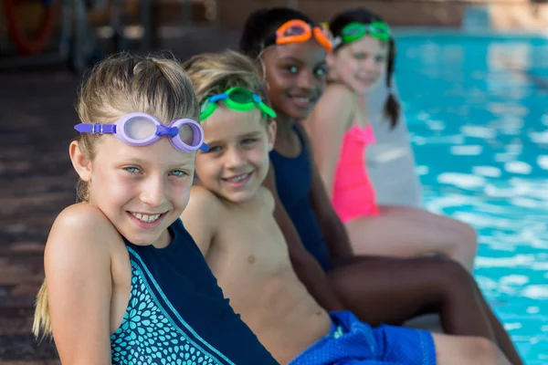 Fila di amici seduti a bordo piscina — Foto Stock