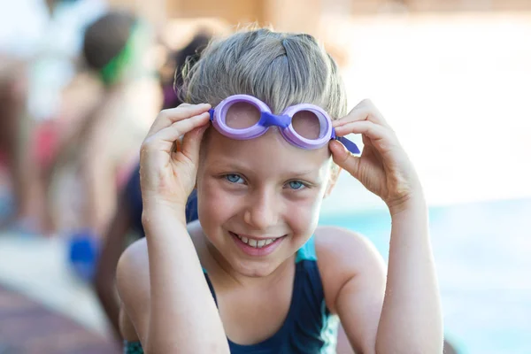 Sonriente niña sosteniendo gafas de natación — Foto de Stock