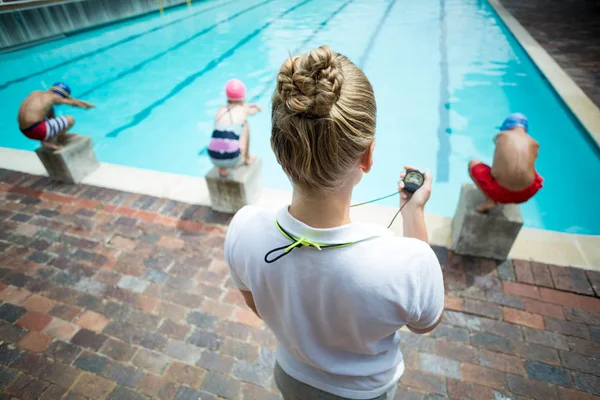 Istruttore femminile monitoraggio dei bambini a bordo piscina — Foto Stock