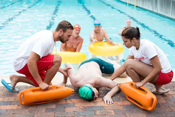 Homens e mulheres salva-vidas ajudando o homem inconsciente — Fotografia de Stock