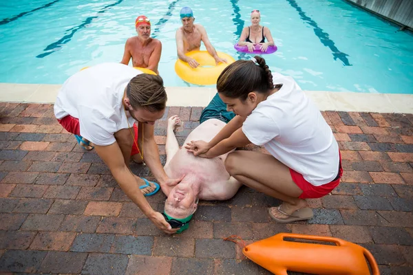 Des secouristes aident un aîné inconscient au bord de la piscine — Photo