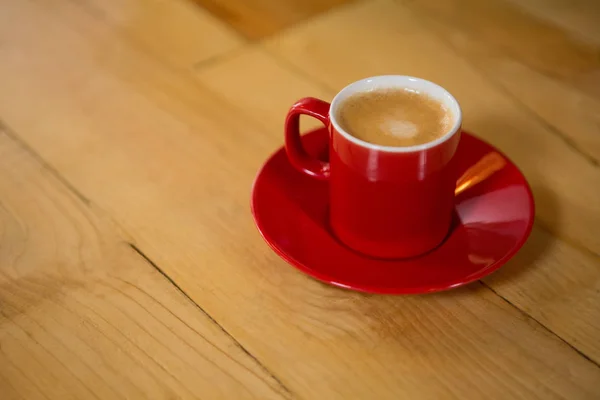 Красная чашка и блюдце на столе в кафе — стоковое фото
