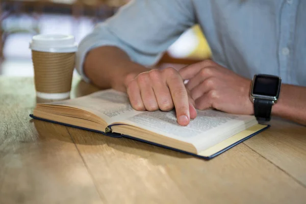 Hombre leyendo libro en la mesa en la cafetería —  Fotos de Stock