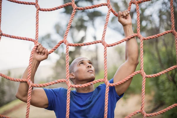 Fit man klimmen net tijdens hindernissenparcours — Stockfoto