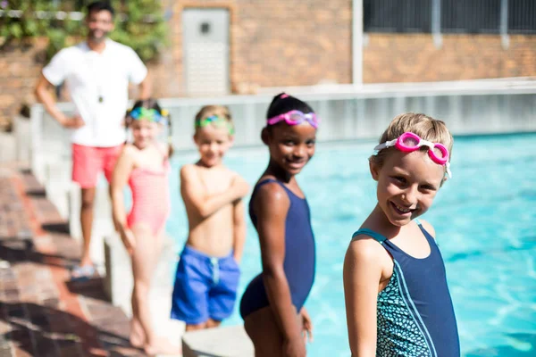 Lilla simmare och manlig instruktör står vid poolkanten — Stockfoto