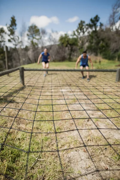 Fit man and woman crawling under net — Stock Photo, Image