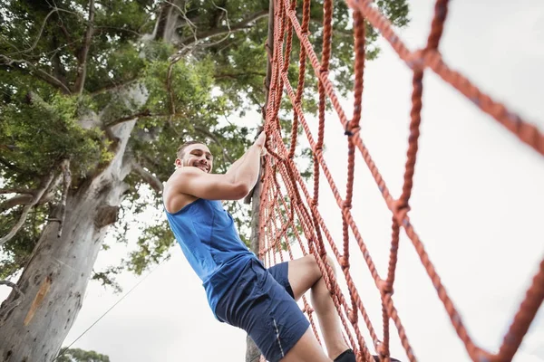 Homme grimpant un filet pendant le parcours d'obstacles — Photo