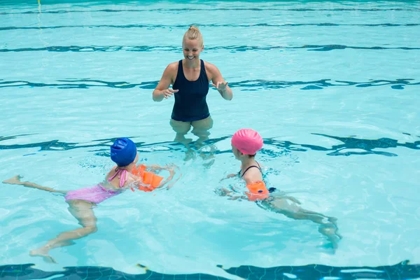 Instrutor assistindo crianças na piscina — Fotografia de Stock