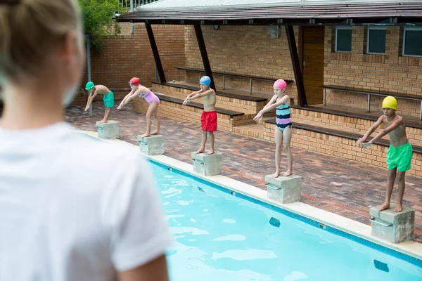 Kobiece trener patrzy na dzieci, przy basenie — Zdjęcie stockowe