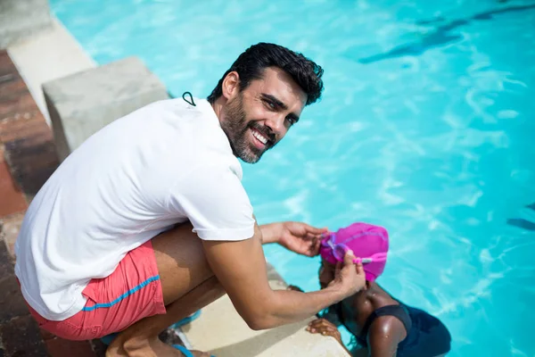 Instrutor masculino assistindo menina na piscina — Fotografia de Stock