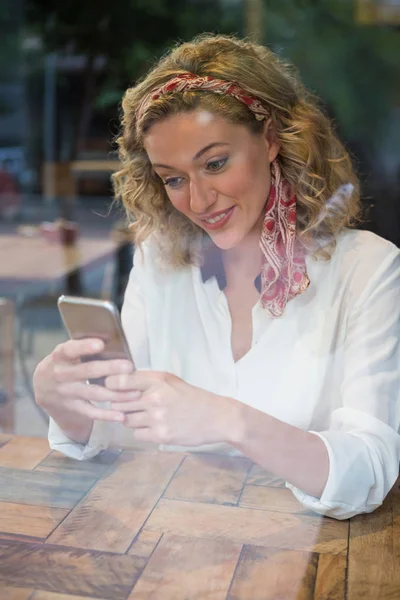 Ung kvinna som använder mobiltelefon på kafé — Stockfoto