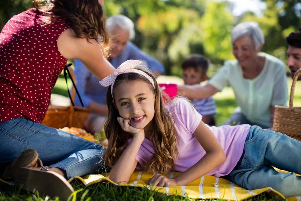 Дівчина на ковдрі крім сім'ї насолоджується пікніком — стокове фото