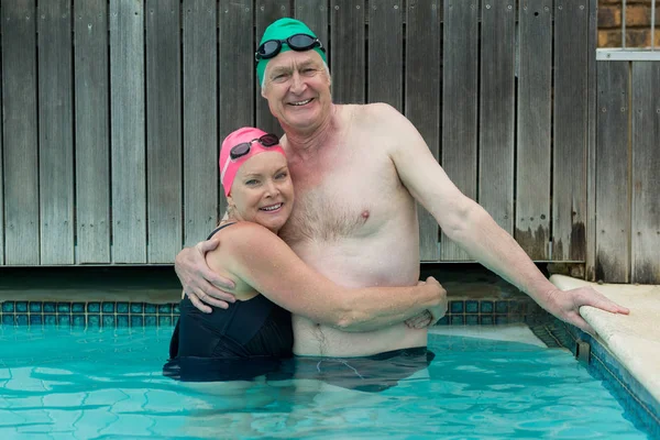 Äldre par omfamnar i poolen — Stockfoto
