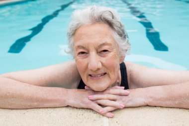 Senior woman leaning on poolside clipart