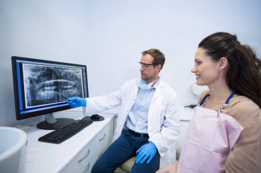 Dentist showing an x-ray of teeth to patient clipart