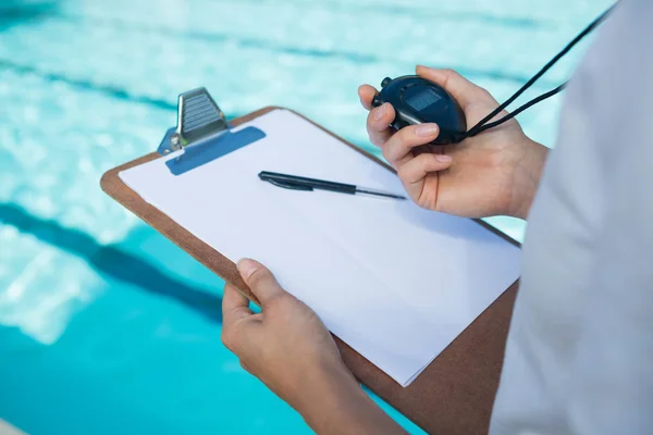 Entrenador de natación mirando cronómetro en la piscina —  Fotos de Stock