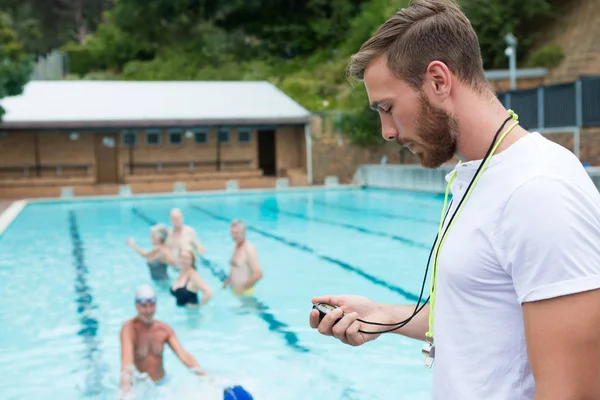 Тренер з плавання дивиться на секундомір біля басейну — стокове фото