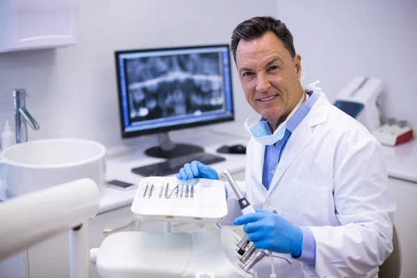 Dentista sorrindo segurando peça de mão dental — Fotografia de Stock