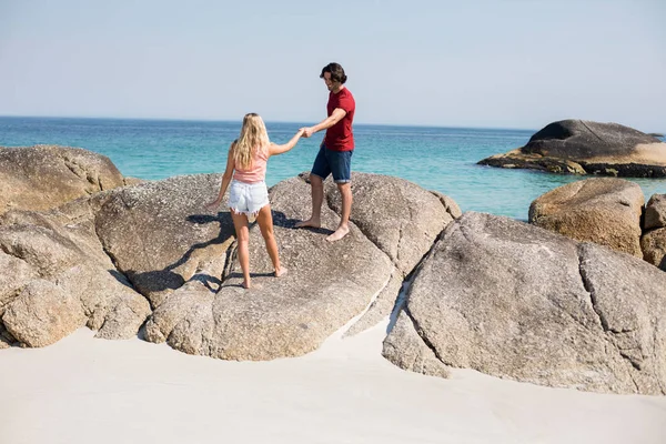 Couple tenant la main sur le rocher à la plage — Photo