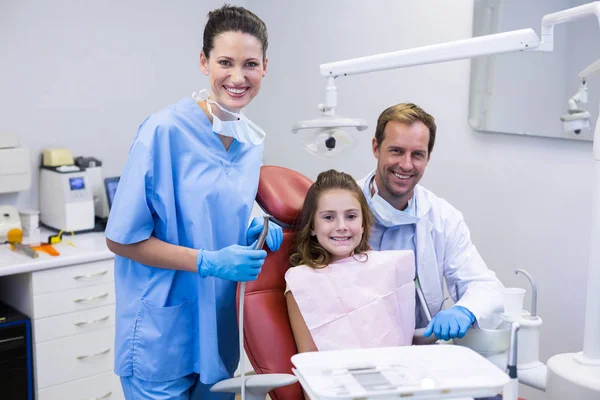 Dentistas sonrientes y paciente joven —  Fotos de Stock