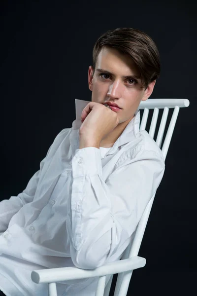 Androgynous homem posando enquanto sentado na cadeira — Fotografia de Stock