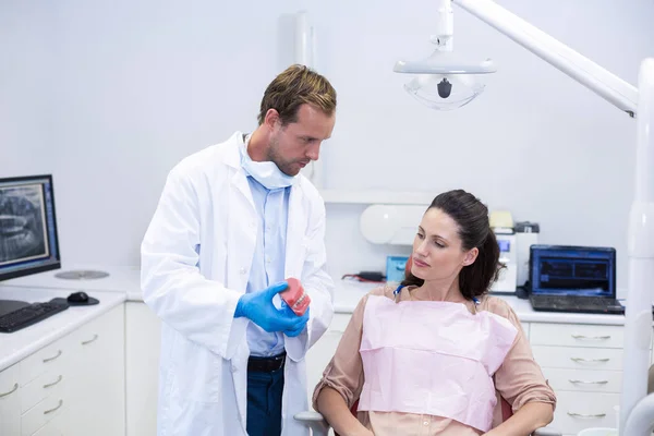 Стоматолог показывает пациенту модельные зубы — стоковое фото
