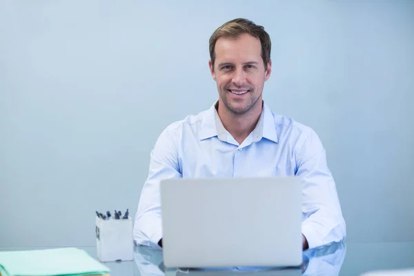 Lachende tandarts die op laptop werkt — Stockfoto