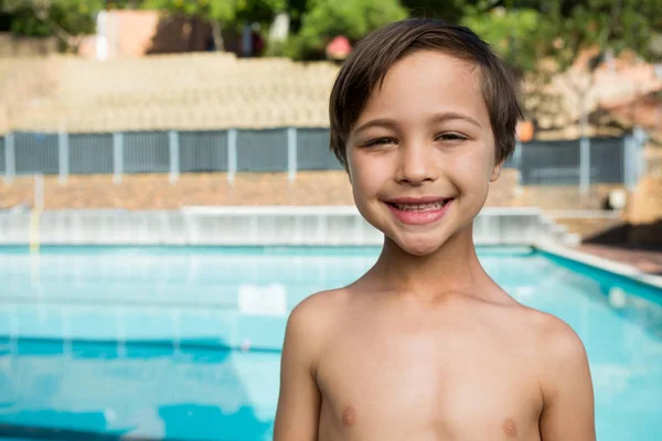Rapaz sorridente de pé perto da piscina — Fotografia de Stock
