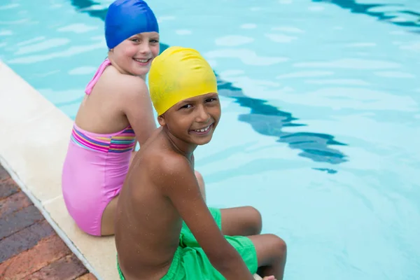 Crianças sorridentes sentadas perto da piscina — Fotografia de Stock
