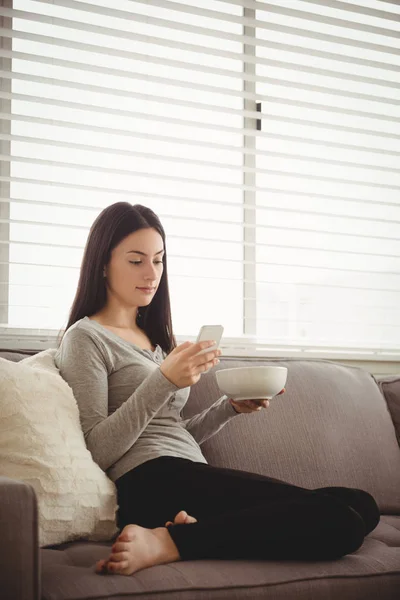 Жінка використовує мобільний телефон, сидячи на дивані — стокове фото