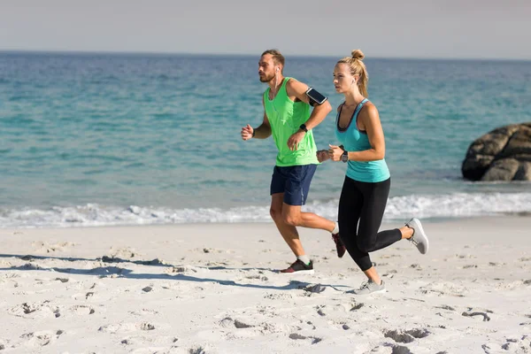 Junges Paar joggt am Strand — Stockfoto
