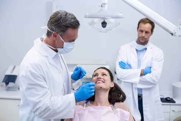 Dentista examinando a una paciente con herramientas — Foto de Stock