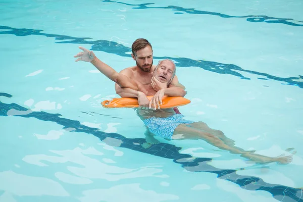 Lifeguard rescuing senior man from pool — Stock Photo, Image