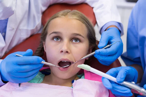 Dentist and nurse examining patient with tools — Stock Photo, Image