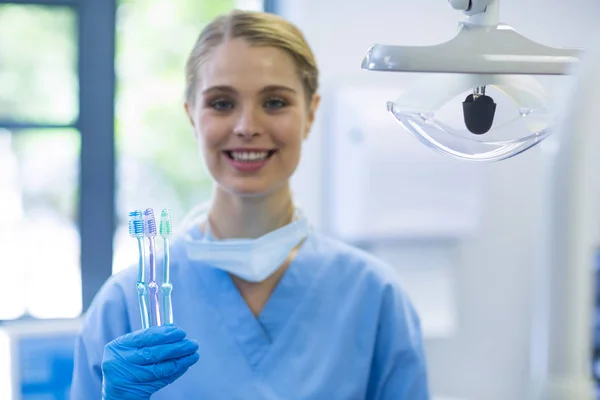 Kvinnlig sjuksköterska innehav tandborstar — Stockfoto