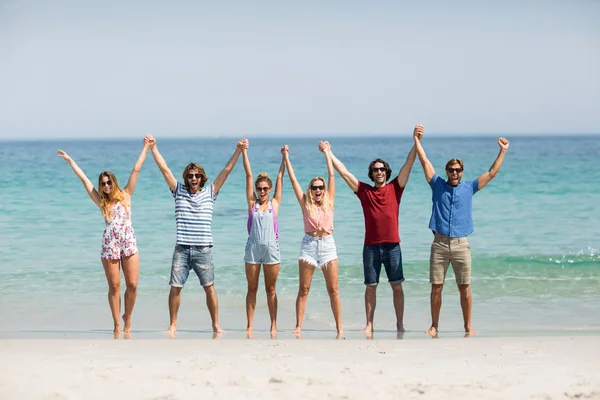 手牵着手与双臂上举在海滩的朋友 — 图库照片