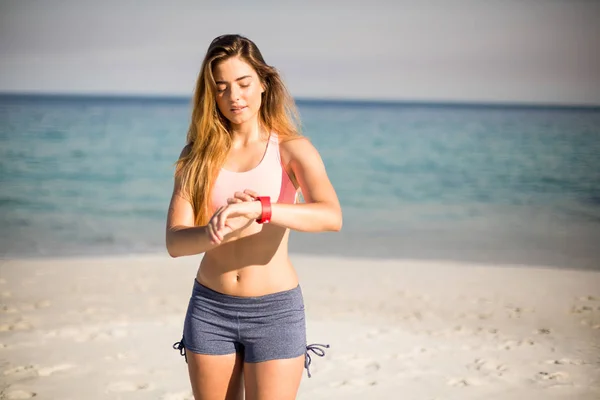 Женщина смотрит в наручные часы на пляже — стоковое фото