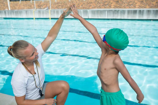 Female trainer training a boy for swimming — Stock Photo, Image