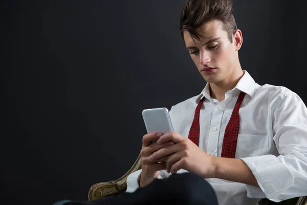 Androgynous man on chair and using phone — Stock Photo, Image