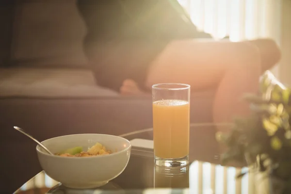 Breakfast on table while woman sitting on sofa — Stock Photo, Image