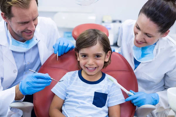 Улыбающиеся дантисты осматривают молодого пациента — стоковое фото