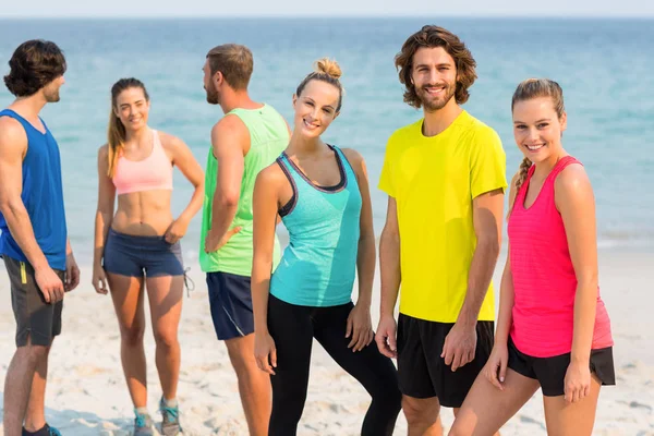 Vrienden in sportkleding staande op strand — Stockfoto